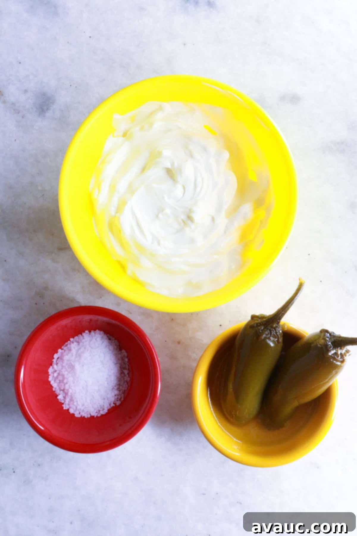 Yellow bowl with sour cream, small bowl with kosher salt, small bowl with 2 pickled jalapeños