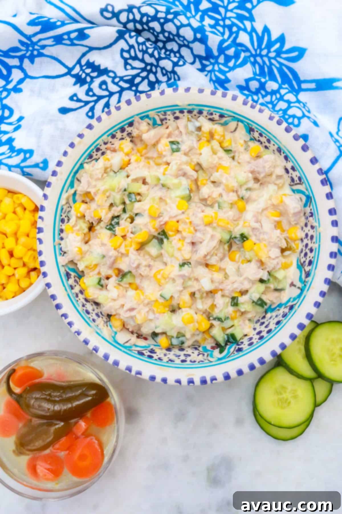 Bowl of Mexican tuna salad with a bowl of corn and another with pickled jalapeños beside it.