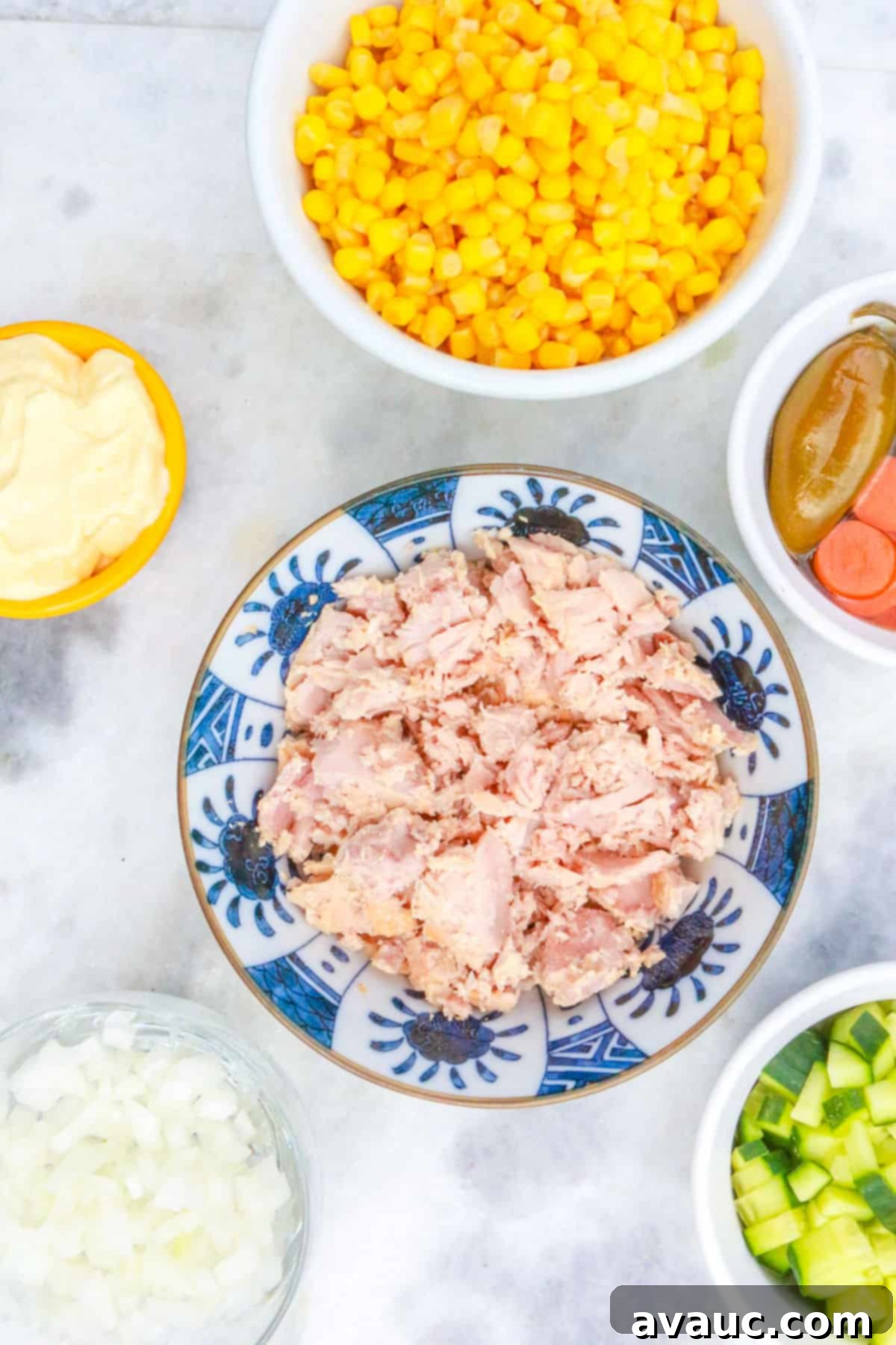 Bowls with canned corn, pickled jalapeños and carrots, diced onion, diced cucumber, canned tuna and mayo.
