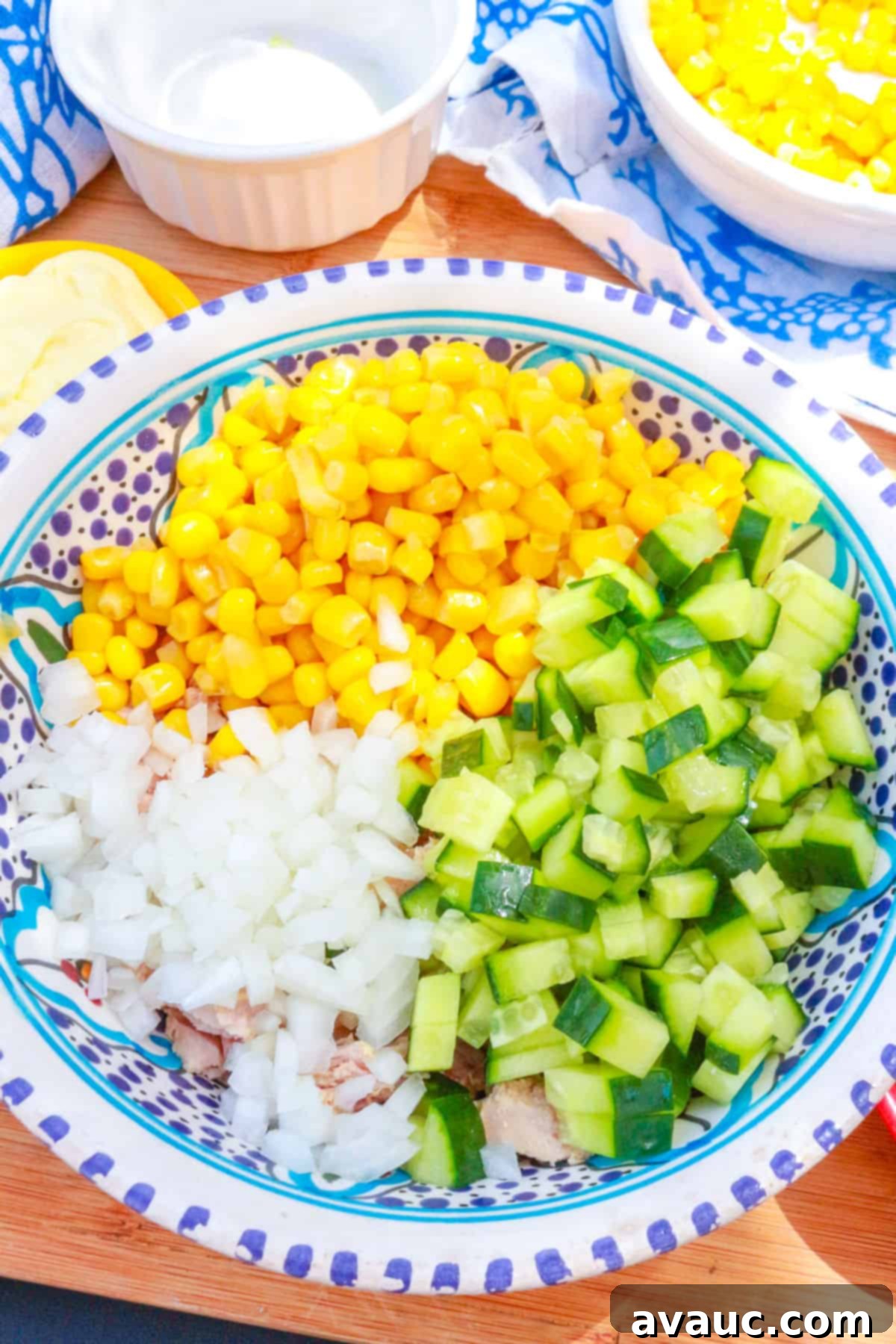 A bowl with canned corn, diced cucumber and diced onion.