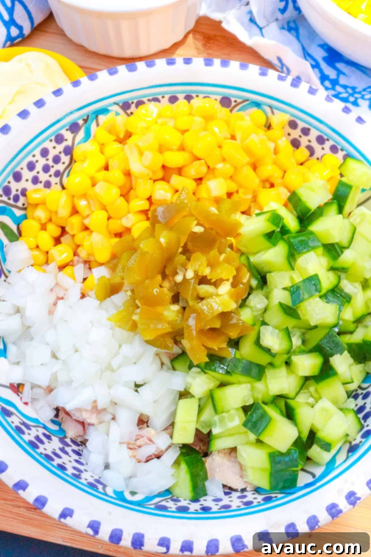 A bowl with canned corn, diced cucumber, diced onion and diced pickled jalapeños.