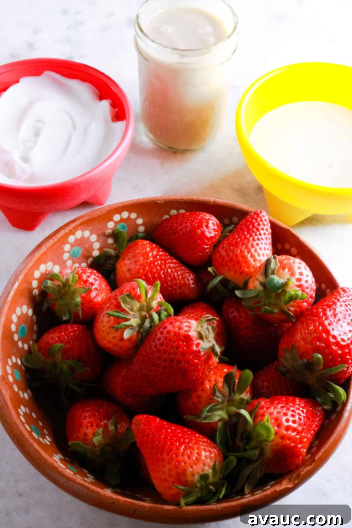 Vegan Strawberry Dream 3 Bowl with coconut yogurt, a jar with coconut condensed milk, a bowl with nutpods and a bowl with strawberries