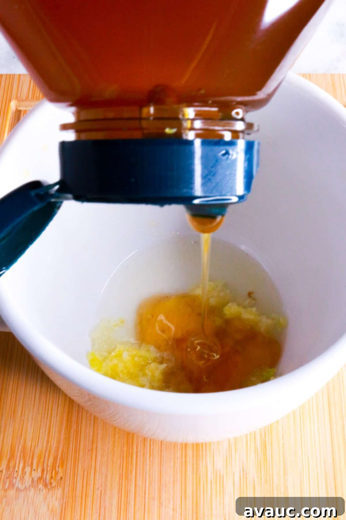 Homemade Garlic Tea Elixir 7 A stream of golden honey being poured from a jar into a white mug, adding sweetness and medicinal properties to the garlic tea.