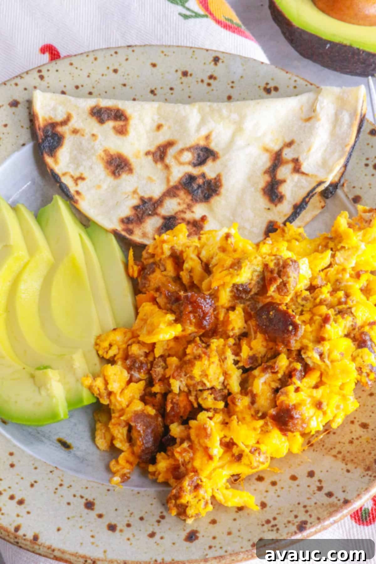 Plate with huevos con chorizo, corn tortilla and sliced avocado