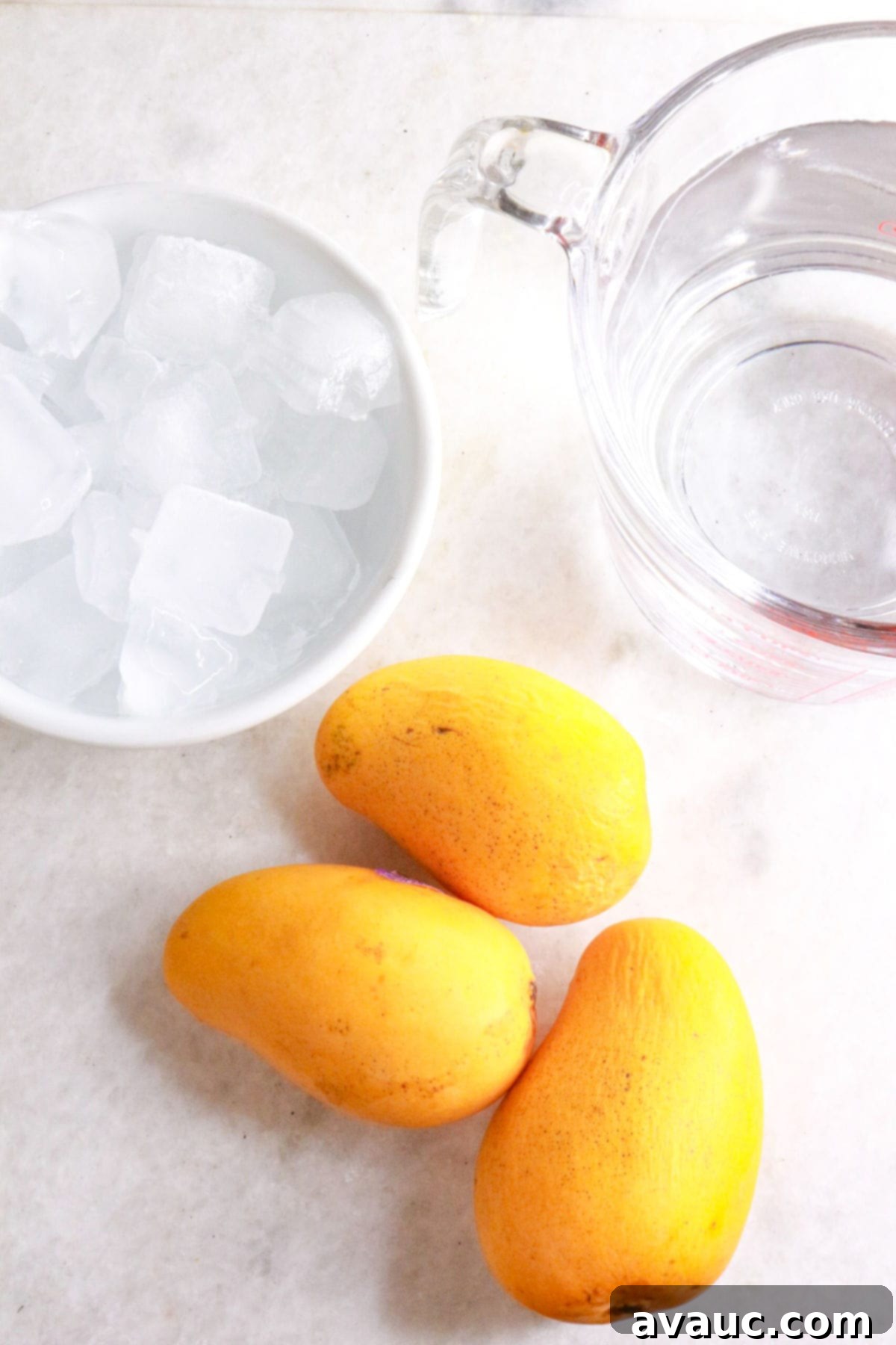 Simple Refreshing Mango Agua Fresca 3 Bowl of ice, container with water and 3 yellow mangos
