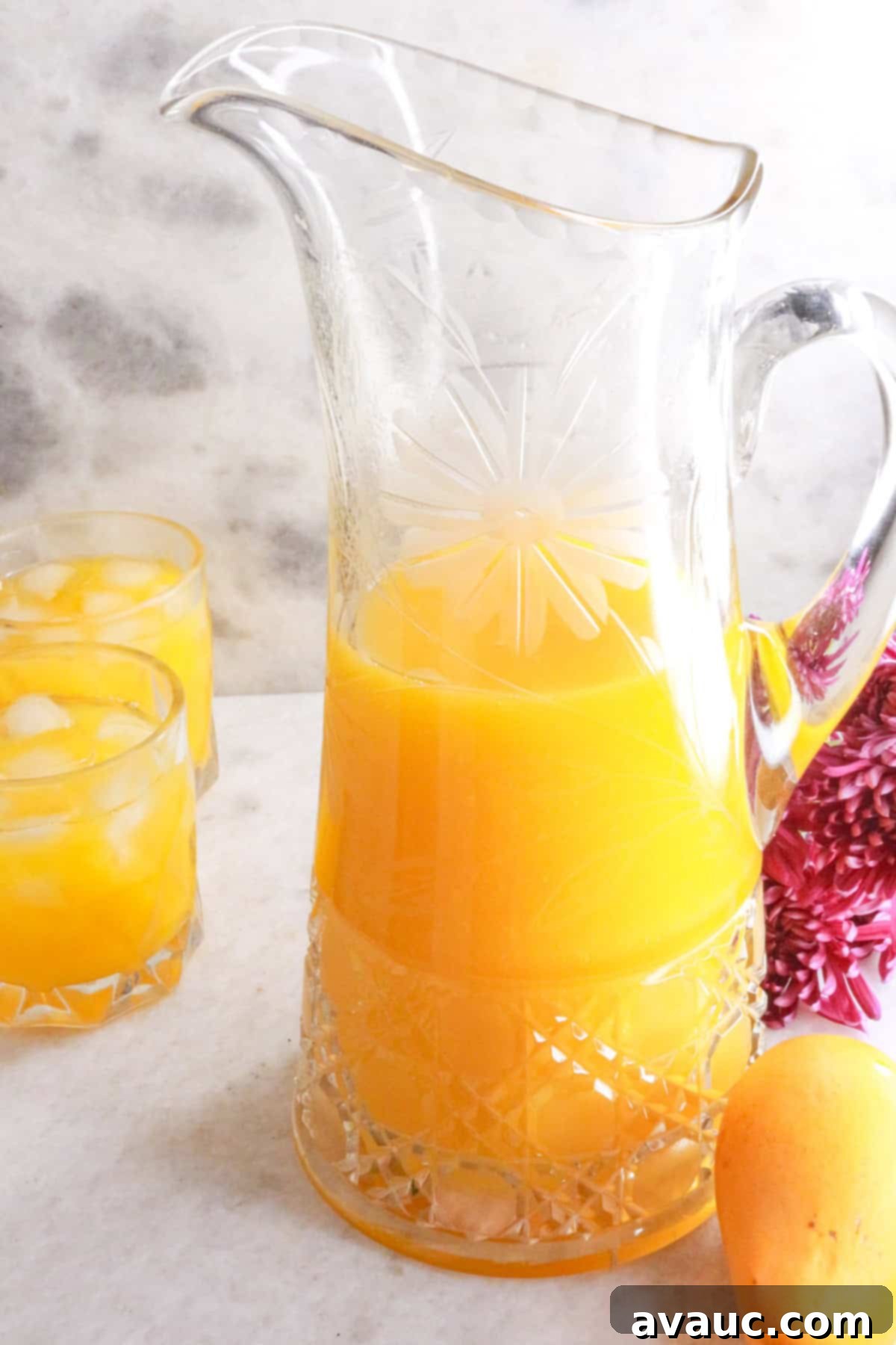 Simple Refreshing Mango Agua Fresca 9 Glass pitcher with mango agua fresca and two glasses in the background
