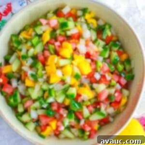 Mango pico de Gallo in a bowl with a mango and wooden spoon by it