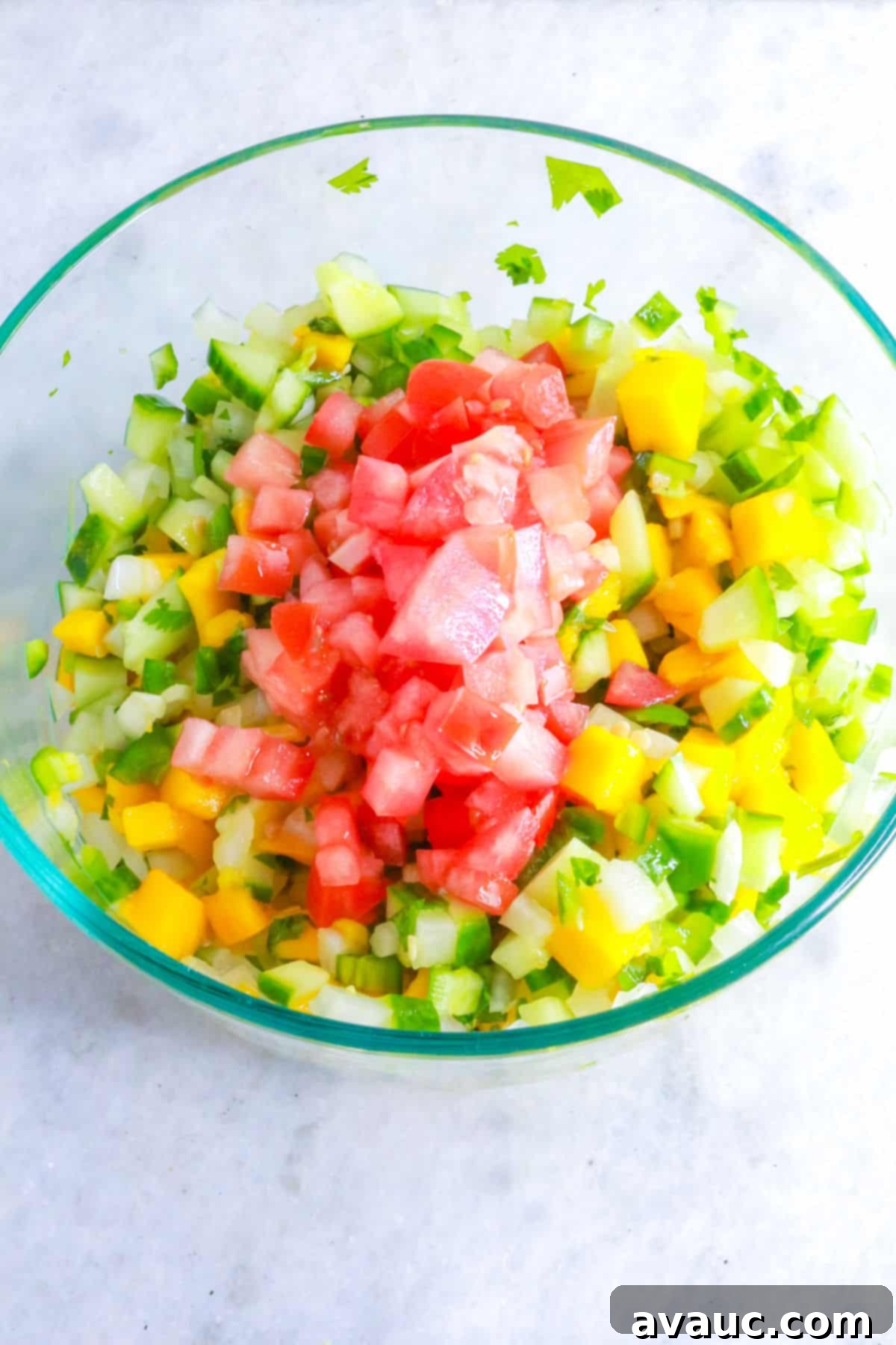 Mixing tomato into mango pico de Gallo