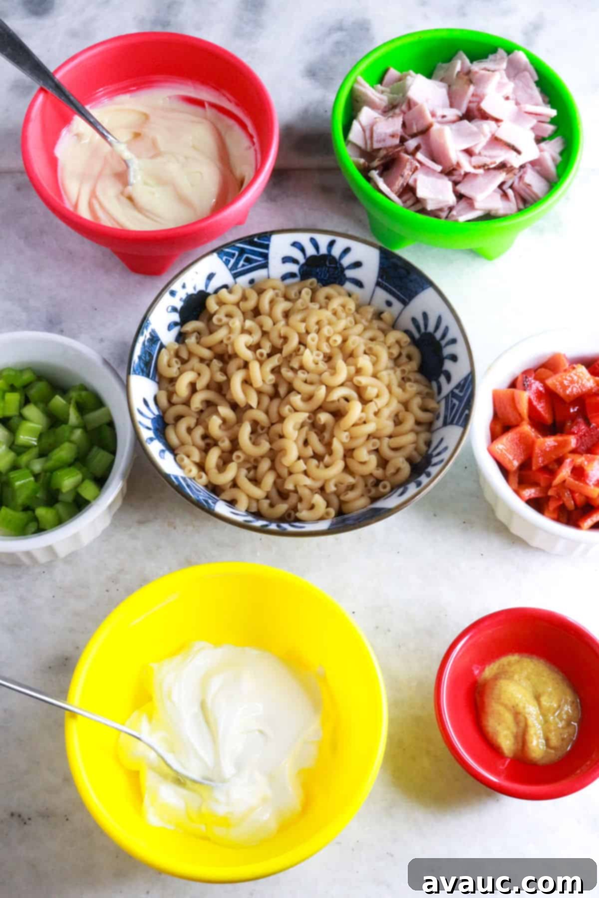 Bowls with sour cream, diced ham, chopped celery, macaroni noodles, roasted bell pepper, mayo, and mustard.