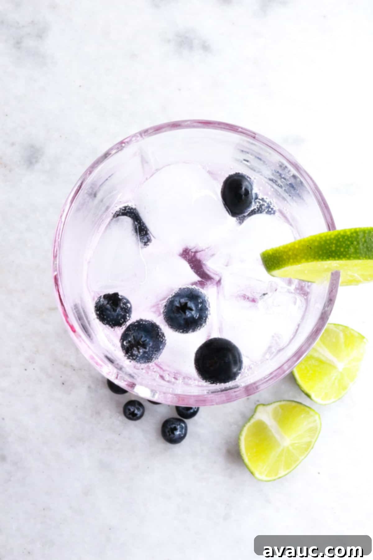Vibrant Berry Refresher 10 Finished blueberry lime mocktail in a tall glass, beautifully garnished with fresh blueberries and a lime slice.
