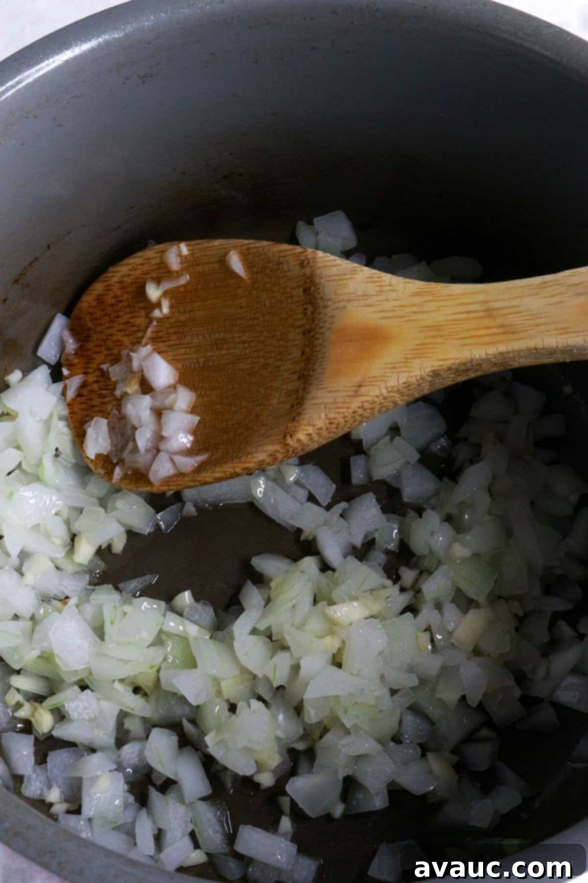 Zesty Mexican White Rice with Sweet Corn 6 Diced garlic and onion being sautéed with a wooden spoon in a saucepan
