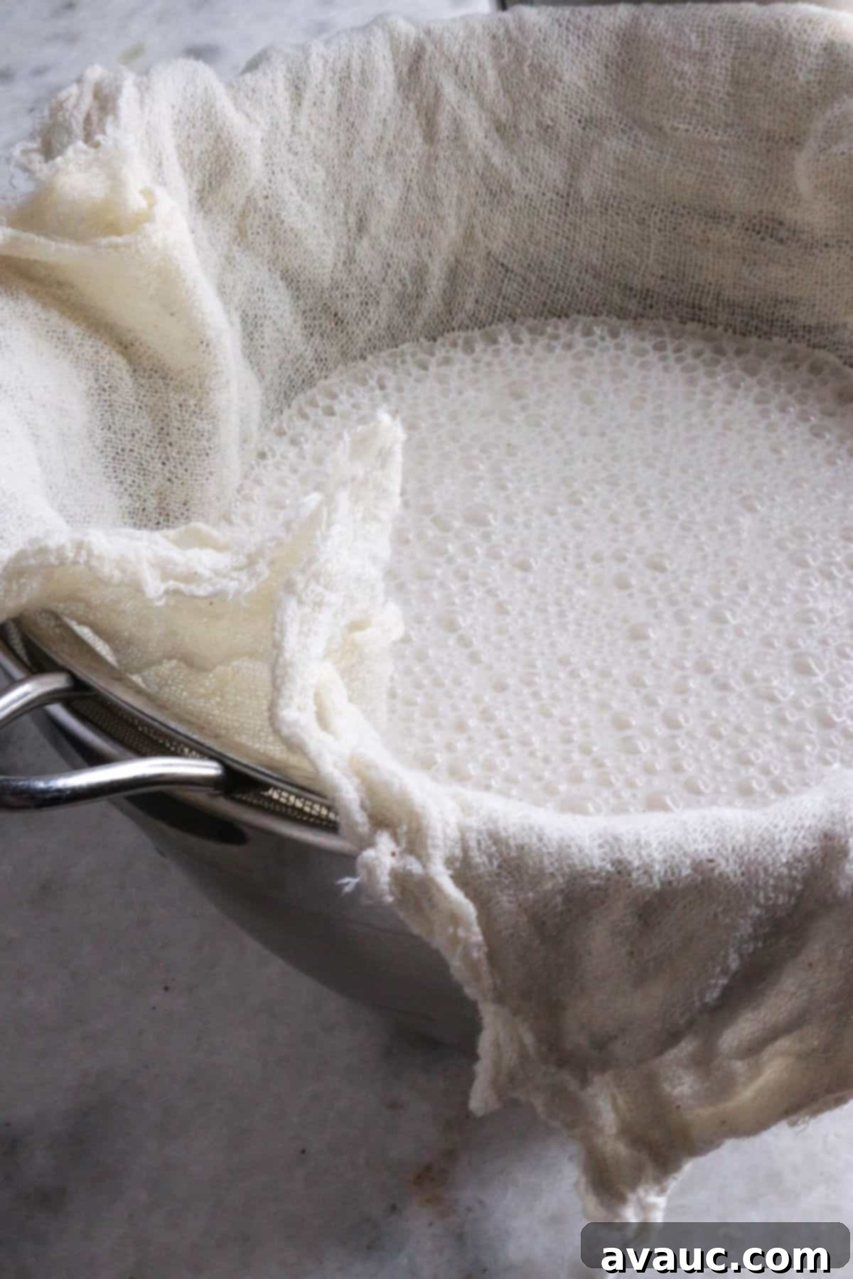 Cooling Horchata Delight 7 Cheesecloth set in a fine mesh strainer over a bowl, ready to strain the blended horchata mixture.