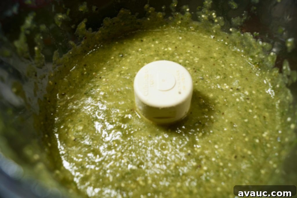 Boiled tomatillos, jalapeños, and onion in a blender, ready for processing