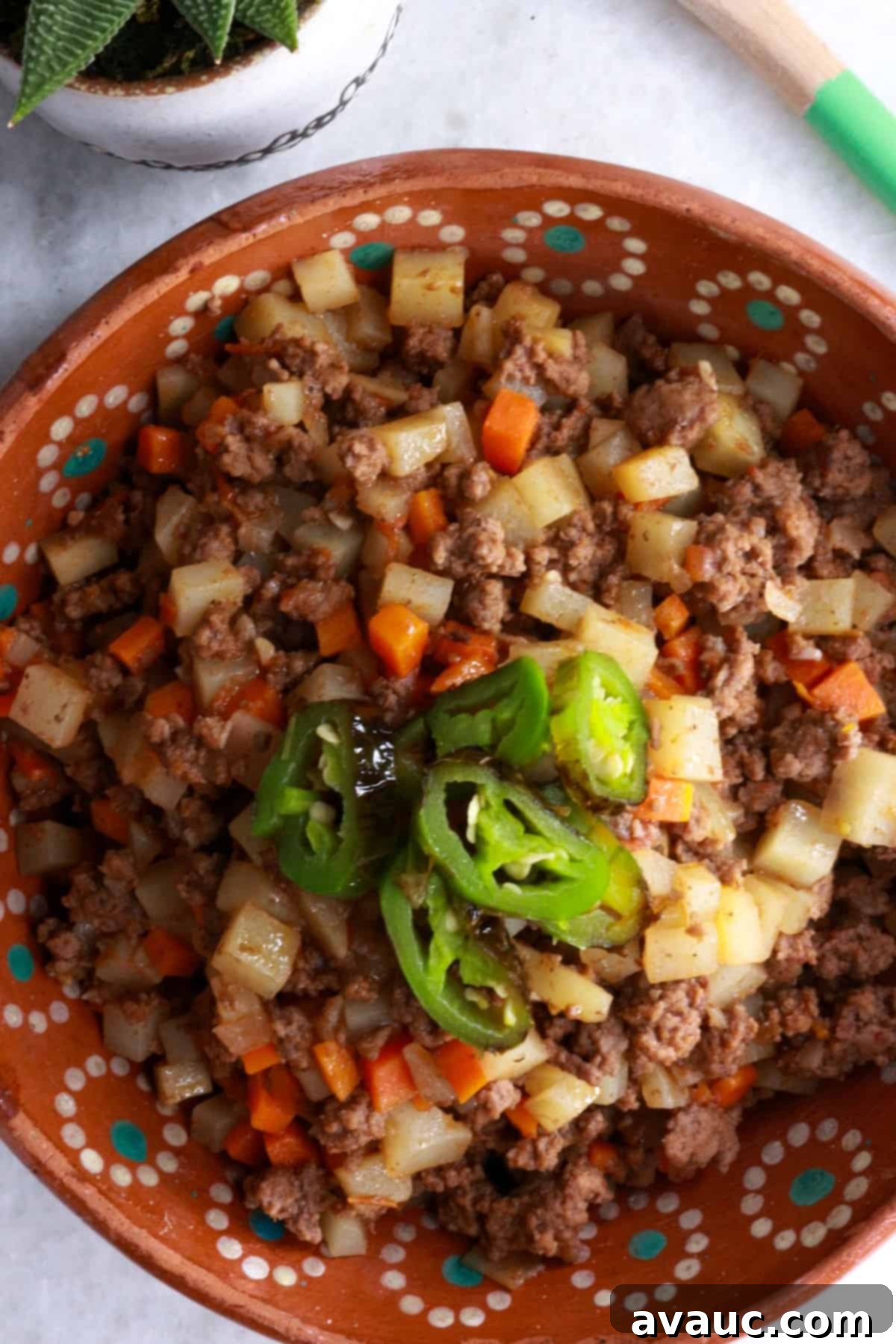 A top-down view of a delicious bowl of Picadillo con Papas, garnished with fresh cilantro, ready to be served on a rustic wooden table.