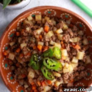Bowl of picadillo con papas topped with sliced jalapeños