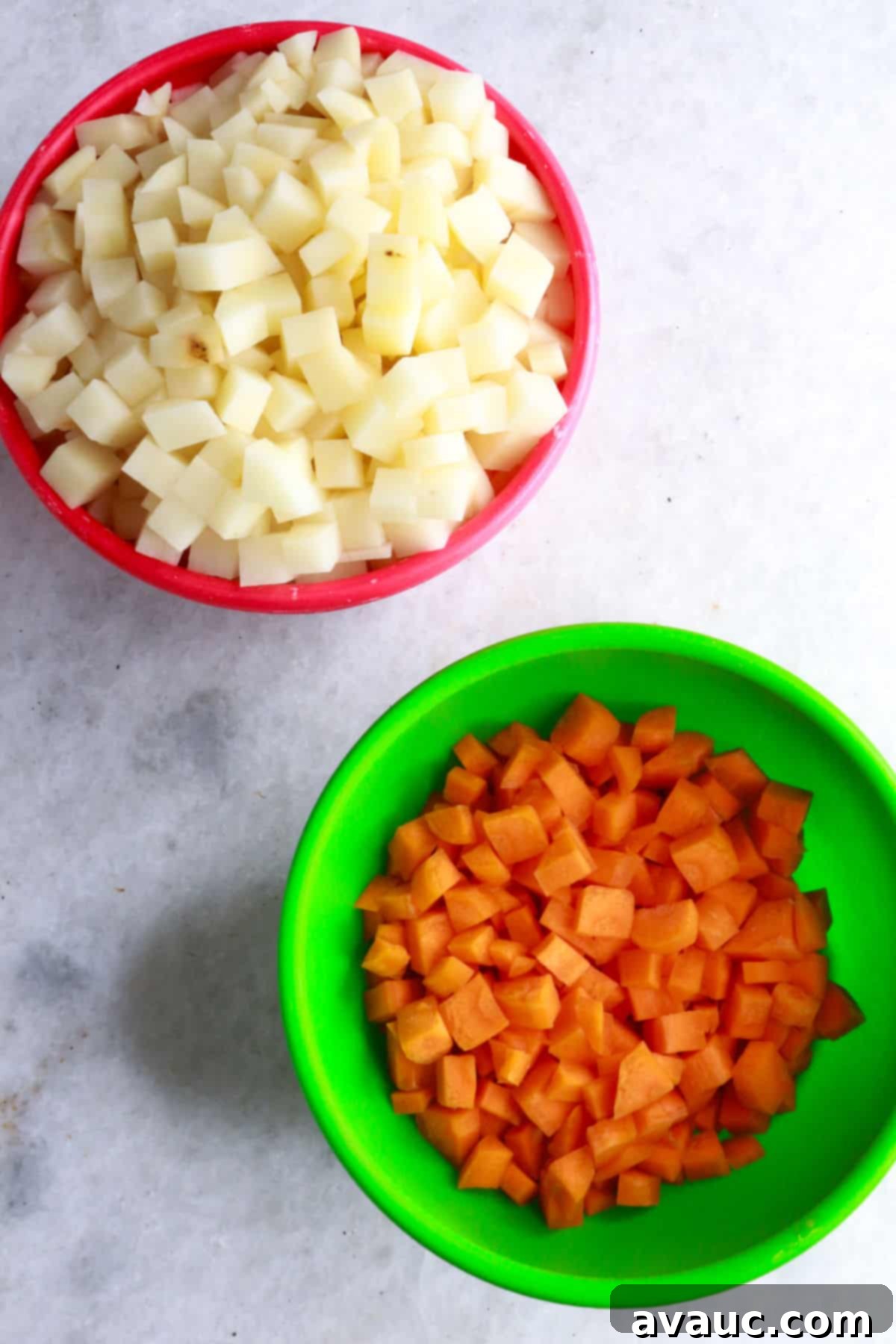 Bowls containing neatly diced potatoes and carrots, ready for cooking.