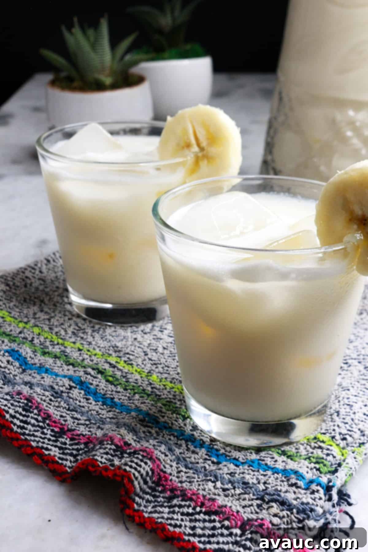 Fresh Banana Drink 2 Two glasses with ice and creamy banana agua fresca garnished with a slice of fresh banana