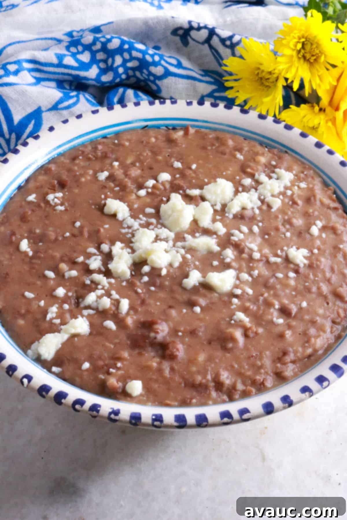 A bowl with creamy refried beans with a some crumbled queso fresco on top
