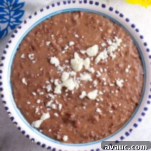 Creamy Frijoles Refritos (Mexican Refried Beans) served in a bowl, garnished with queso fresco.