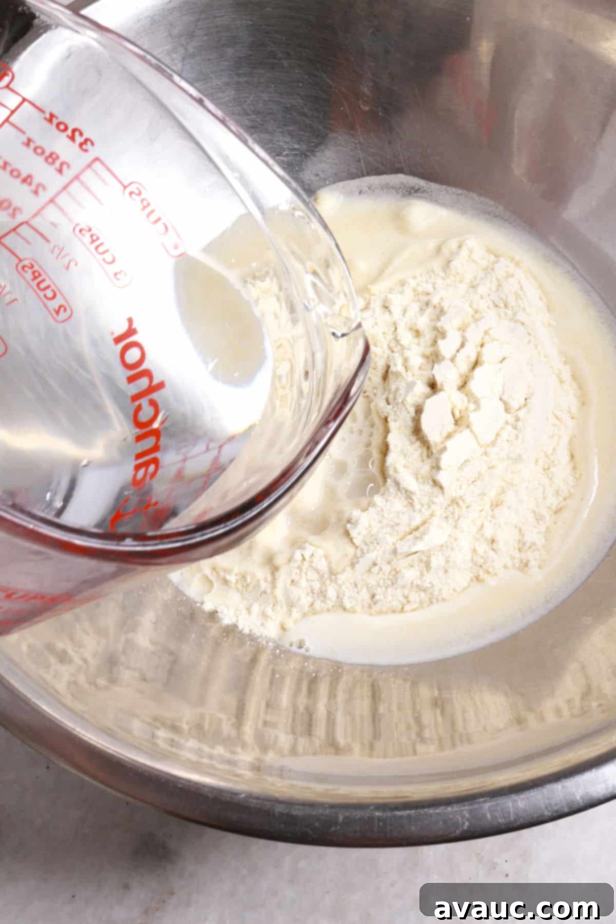 Pouring warm water into a bowl containing masa harina and salt