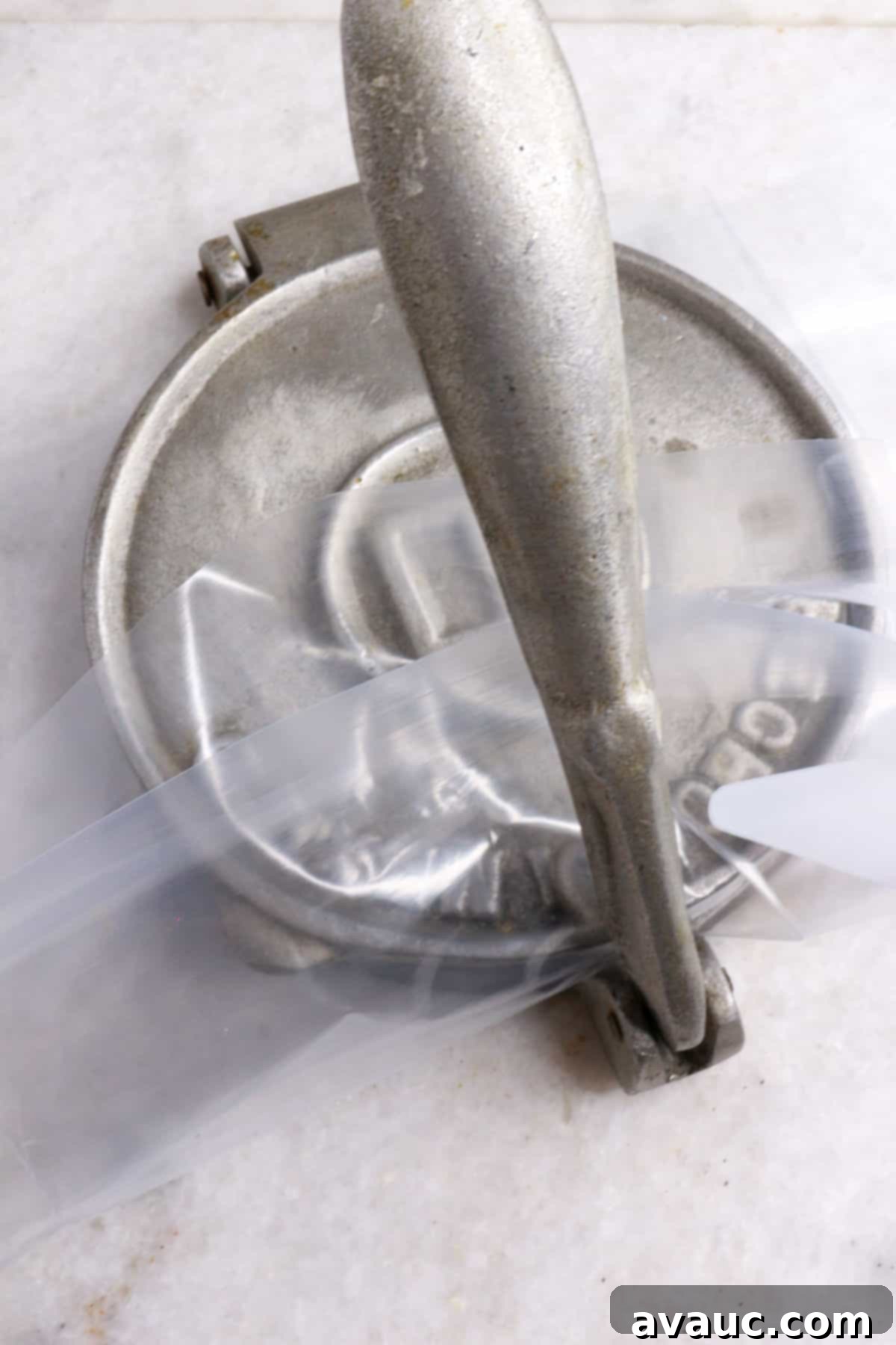 A closed tortilla press flattening a ball of masa dough into a thick disc
