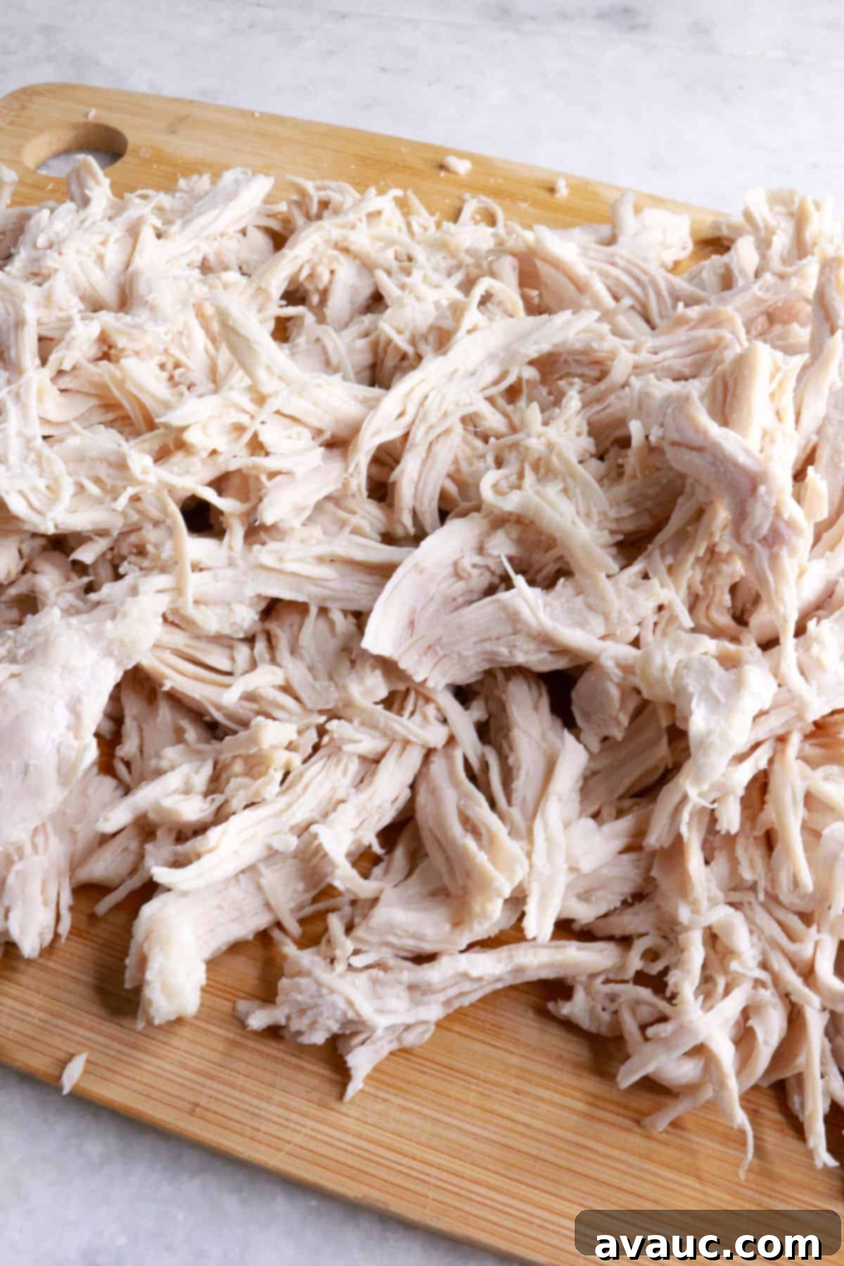 Crunchy Golden Chicken Tacos 5 Finely shredded cooked chicken resting on a wooden cutting board, prepared for the taco filling