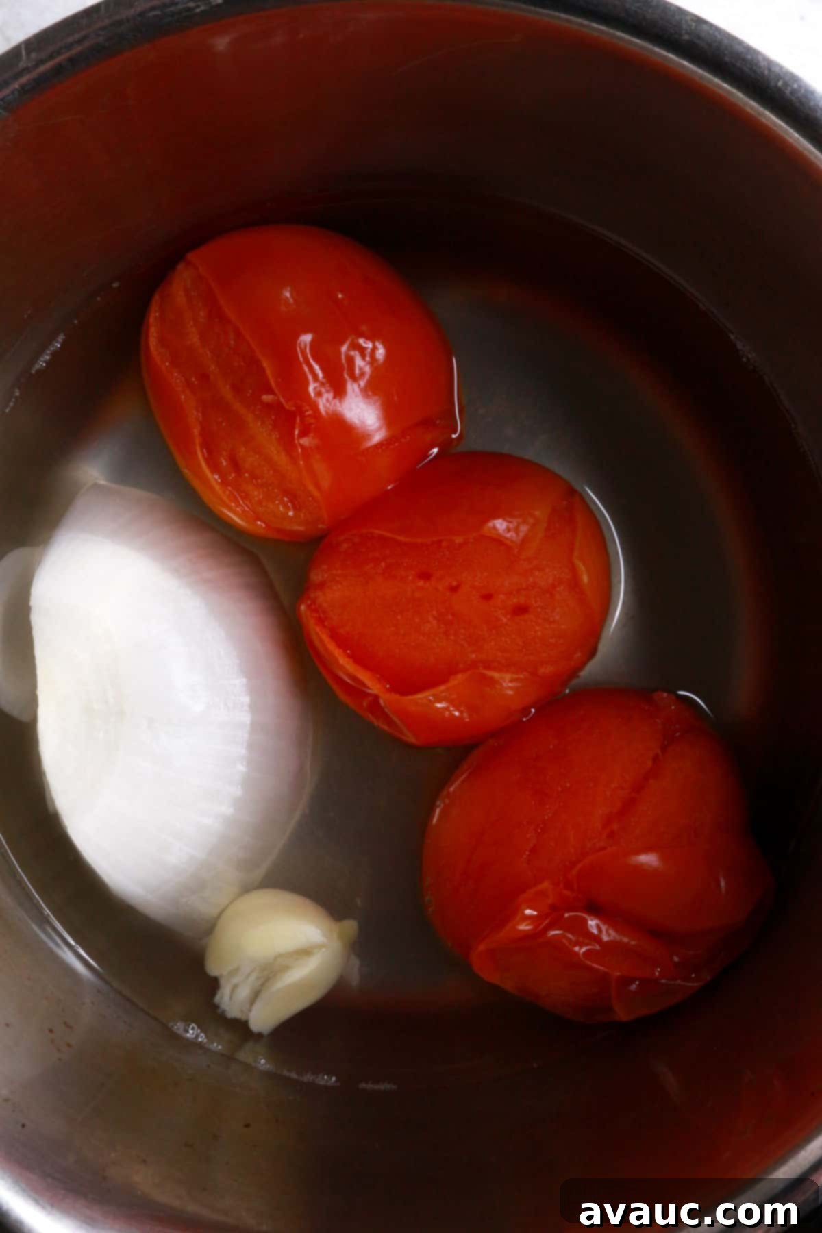 Crunchy Golden Chicken Tacos 6 Three Roma tomatoes, a quarter piece of onion, and a large garlic clove boiling in a small pot with water, softening for the sauce