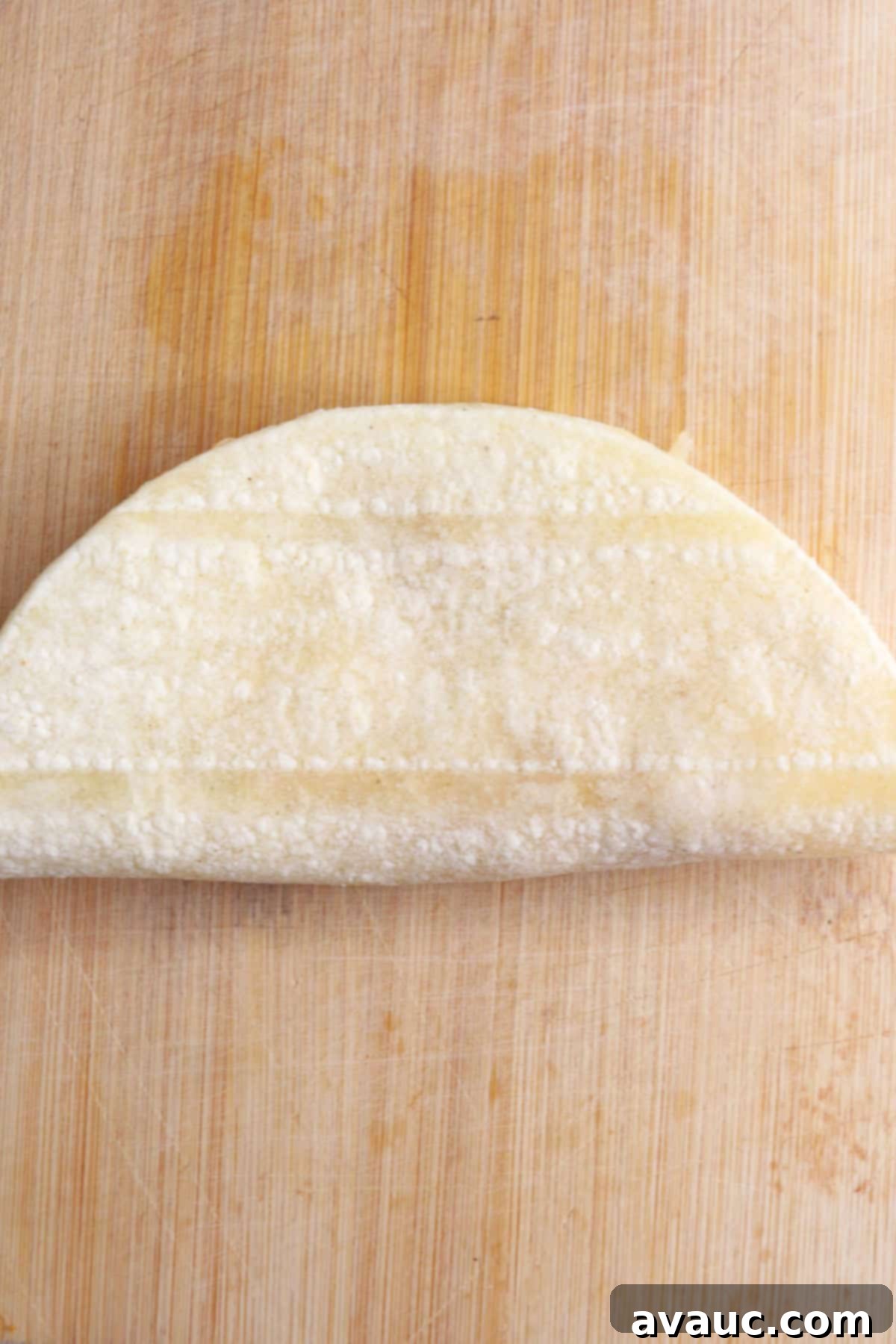 Crunchy Golden Chicken Tacos 10 A perfectly folded half-moon shaped taco, securely filled with chicken and cheese, awaiting its turn in the frying pan