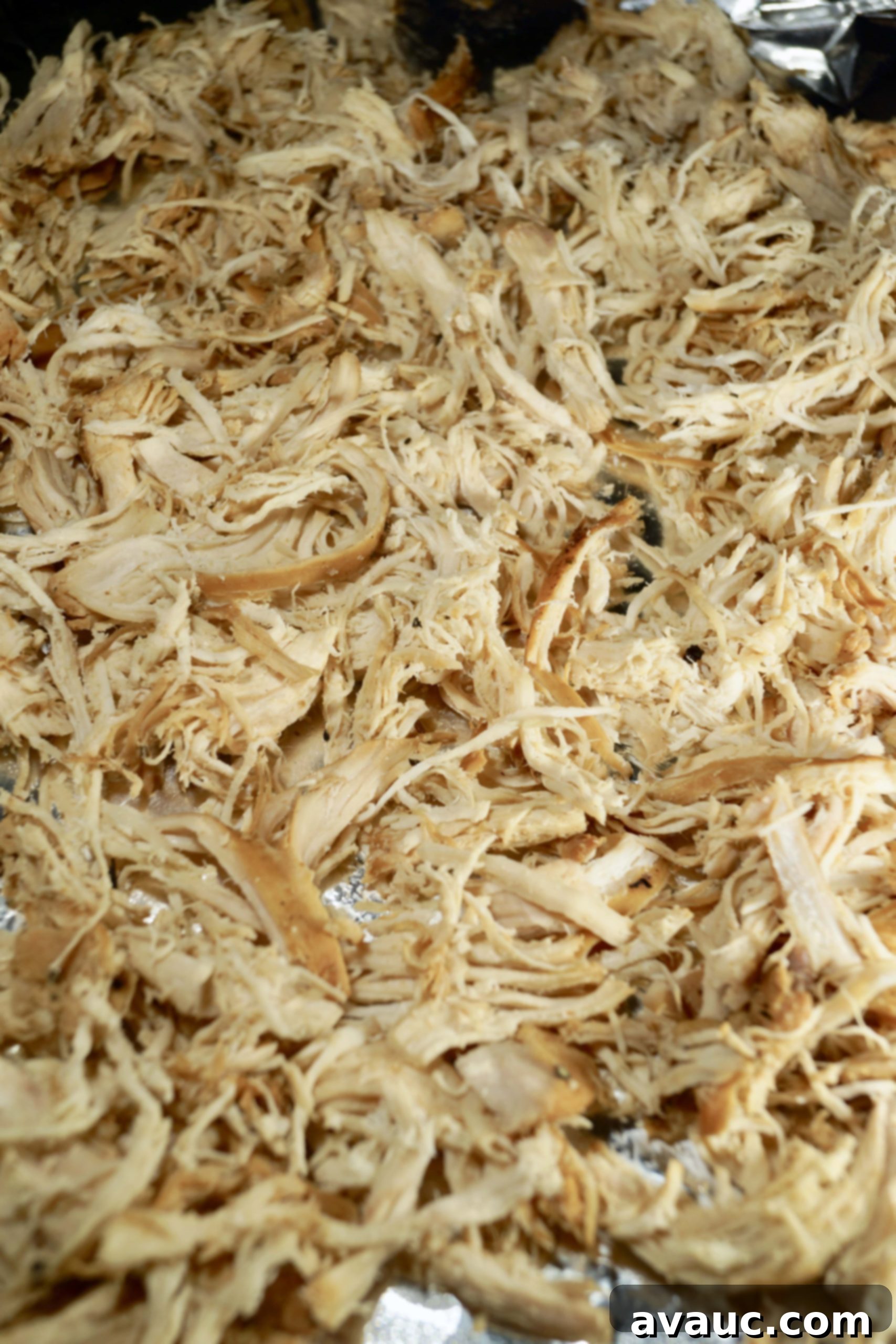 Perfectly shredded slow cooker chicken ready for broiling, showcasing its tender texture. #shreddedchicken #whole30chickentacos