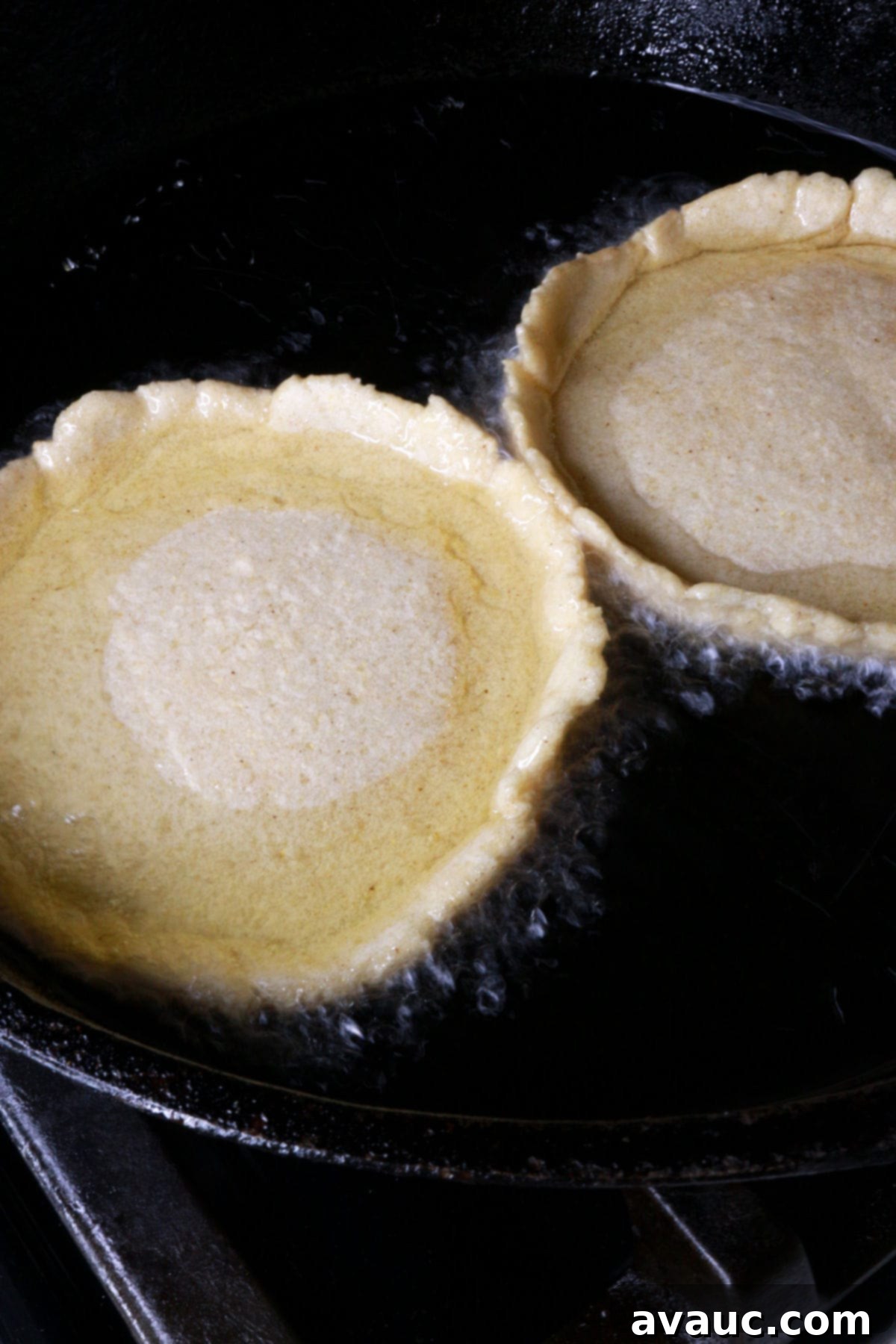 Two sopes face up in frying pan with oil