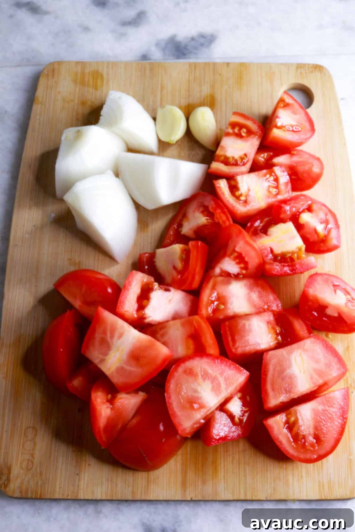 Delicious Gluten-Free Mexican Fideo Soup 4 A wooden cutting board with chopped onion, chopped tomatoes and garlic cloves