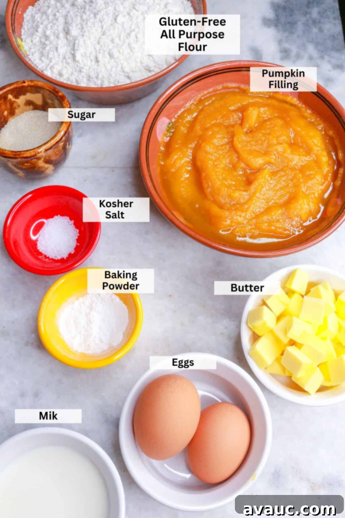 Ingredients for gluten-free pumpkin empanadas: A bowl of pumpkin puree, a bowl of gluten-free flour, sugar, baking powder, salt, two eggs, butter in cubes and milk