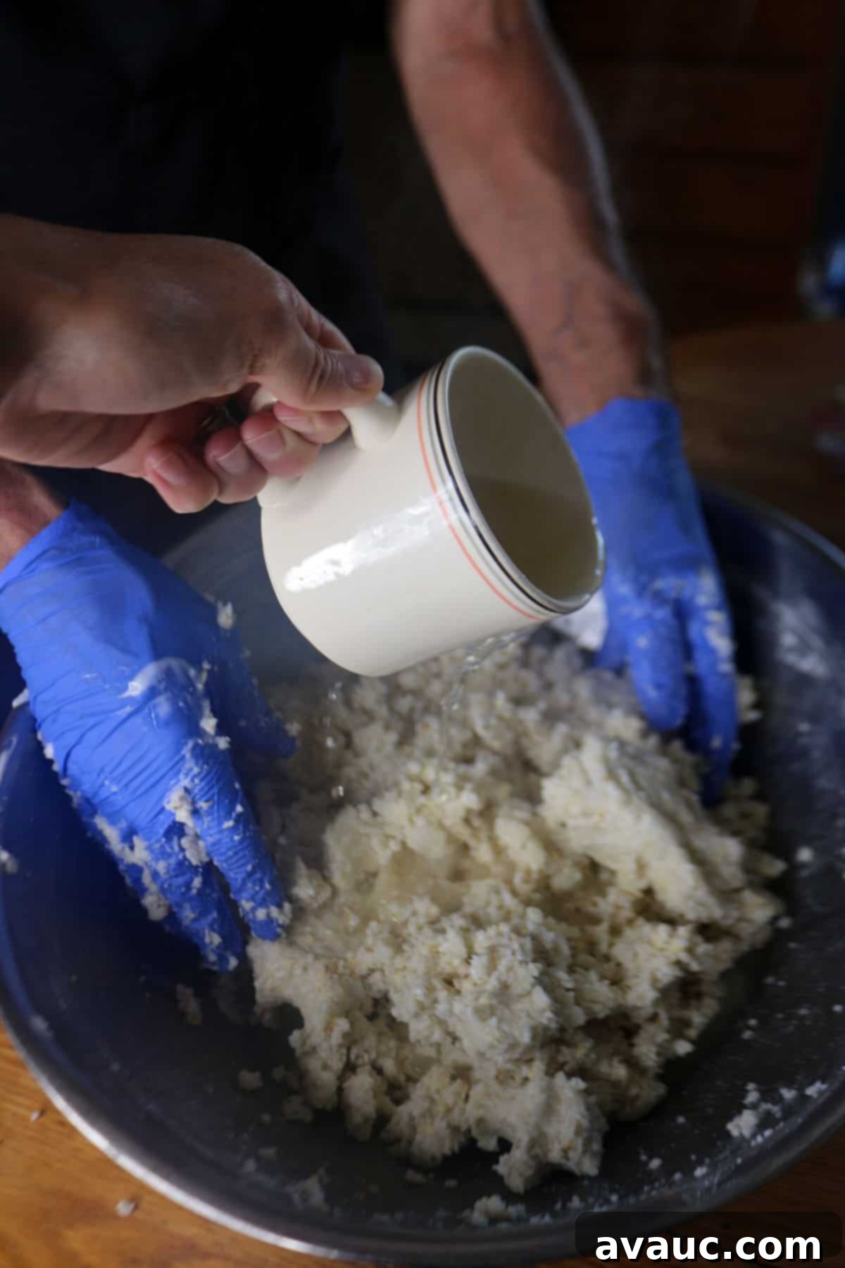 Mastering Nixtamalization for Authentic Tamales 11 Adding warm broth to the masa mixture, gradually kneading it in to achieve the perfect consistency for tamales.