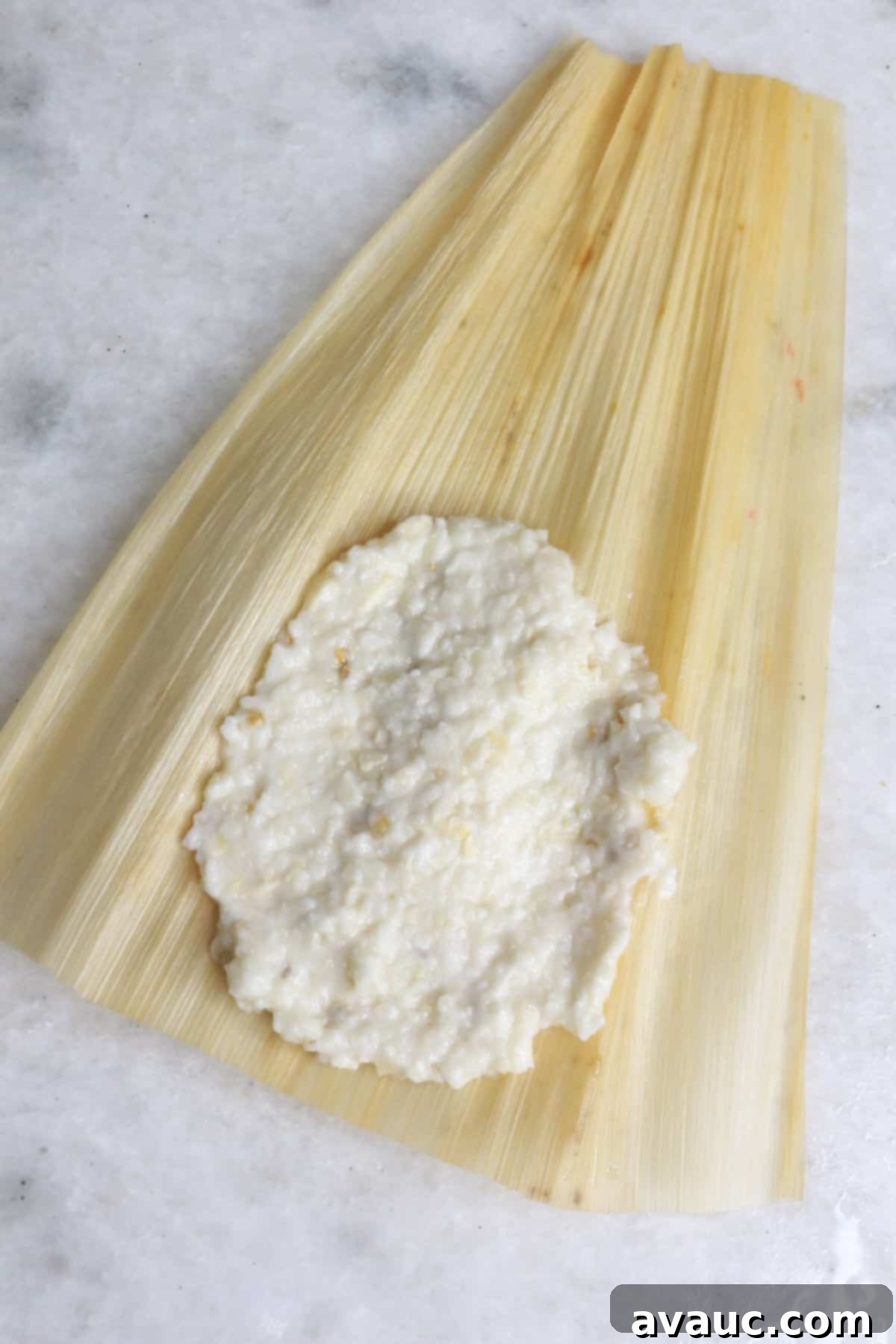 Mastering Nixtamalization for Authentic Tamales 12 Perfectly prepared masa for tamales, spread thinly and evenly on a rehydrated corn husk, ready for filling.