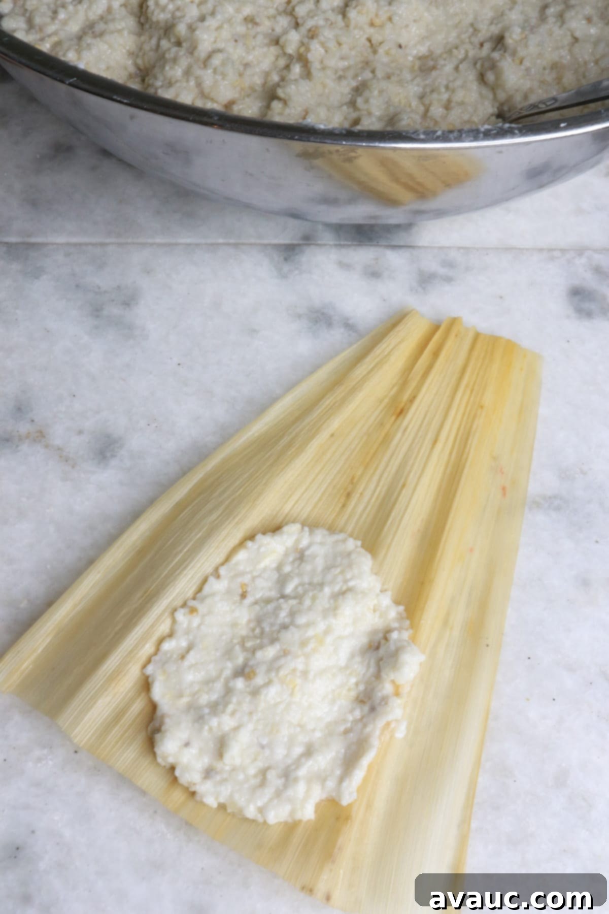 Mastering Nixtamalization for Authentic Tamales 13 A corn husk with masa for tamales spread on it, with a generous amount of fresh masa in a large bowl in the background.