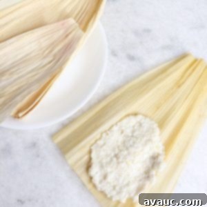 Mastering Nixtamalization for Authentic Tamales 14 A corn husk with masa spread on it, and more corn husks on a plate behind it, showcasing the ready-to-fill tamale dough.