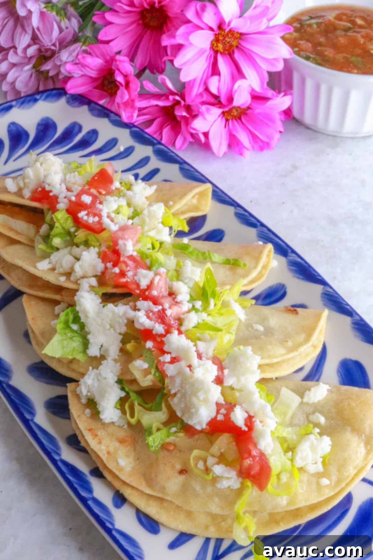 Golden Crispy Bean Tacos 9 Side view of Tacos dorados de frijoles in a row on a platter, topped with lettuce, tomatoes and queso fresco