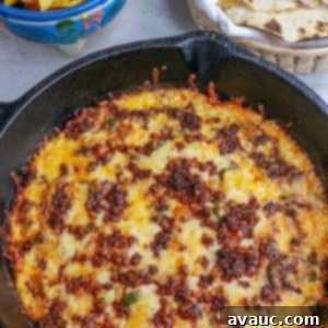 Spicy Chorizo Queso Dip 11 A cast-iron skillet filled with bubbling, melted Choriqueso, garnished with cilantro, next to a bowl of tortilla chips and warm tortillas.
