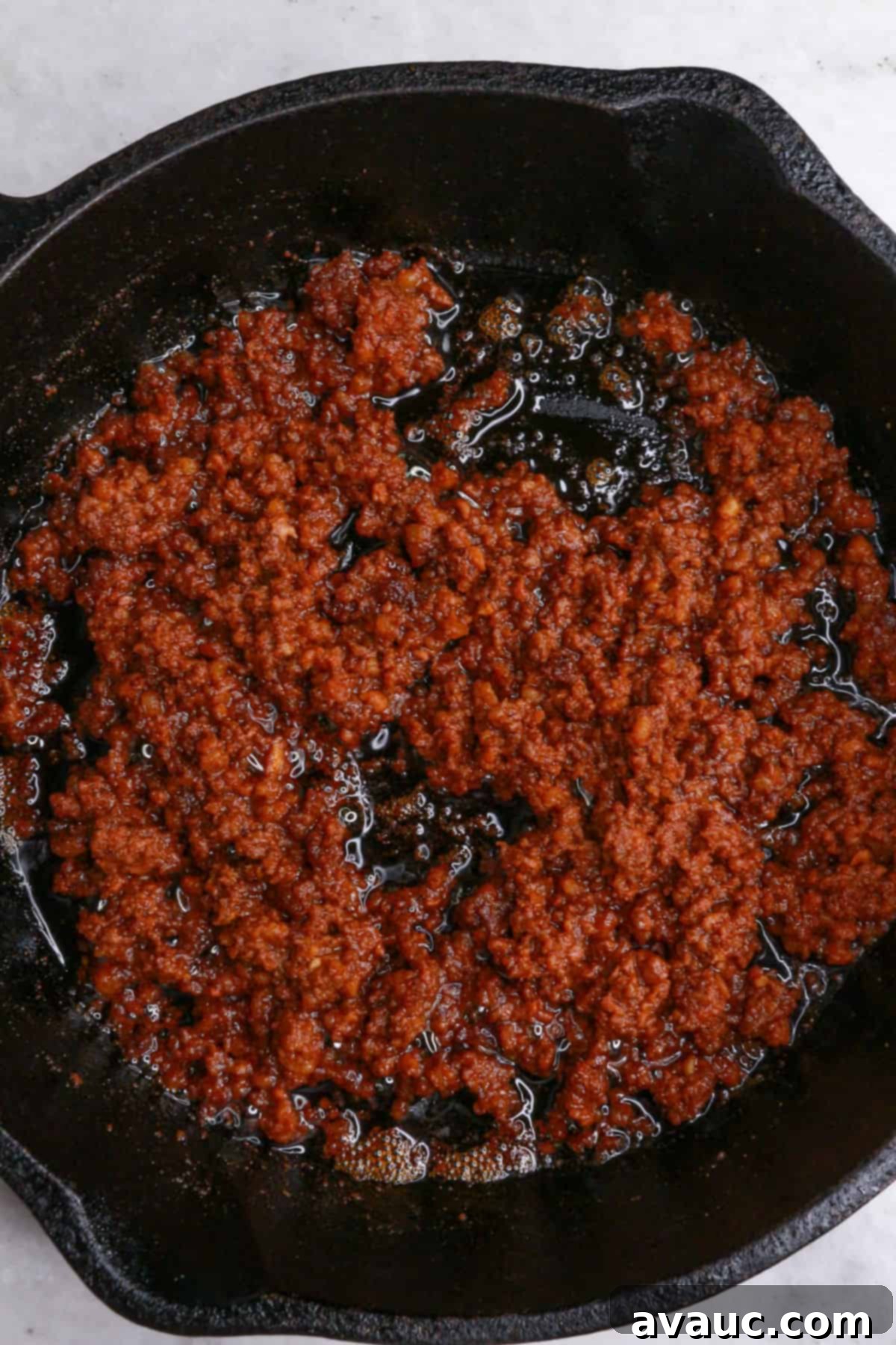 Spicy Chorizo Queso Dip 4 Cooked, crumbled Mexican chorizo sizzling in a cast-iron skillet, ready for the next step of making choriqueso.