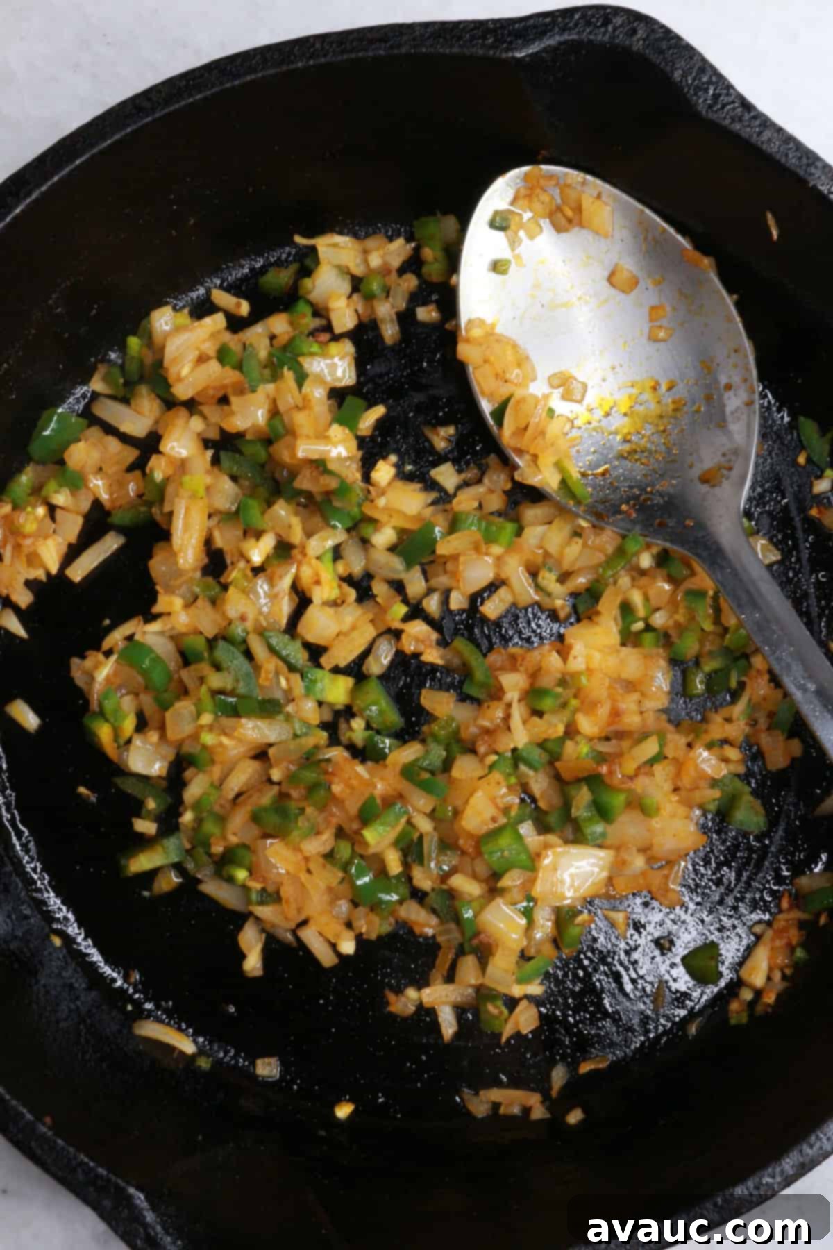 Spicy Chorizo Queso Dip 6 Diced onions, jalapeño, and garlic sautéing in a cast-iron skillet, filling the air with their aromatic fragrance.