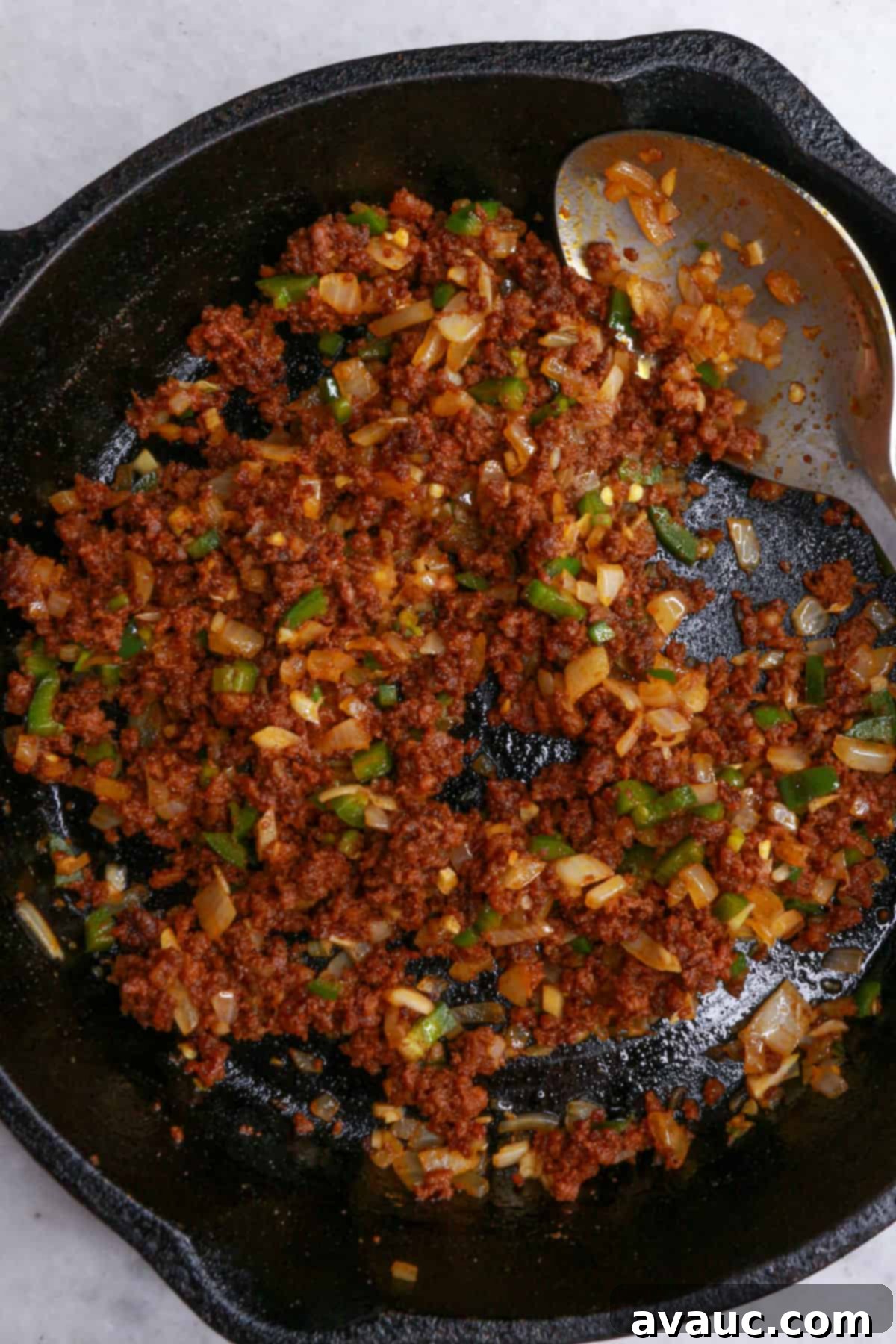Spicy Chorizo Queso Dip 7 Cooked chorizo mixed with sautéed onions, jalapeño, and garlic in a cast-iron skillet, creating a flavorful base for the cheese dip.