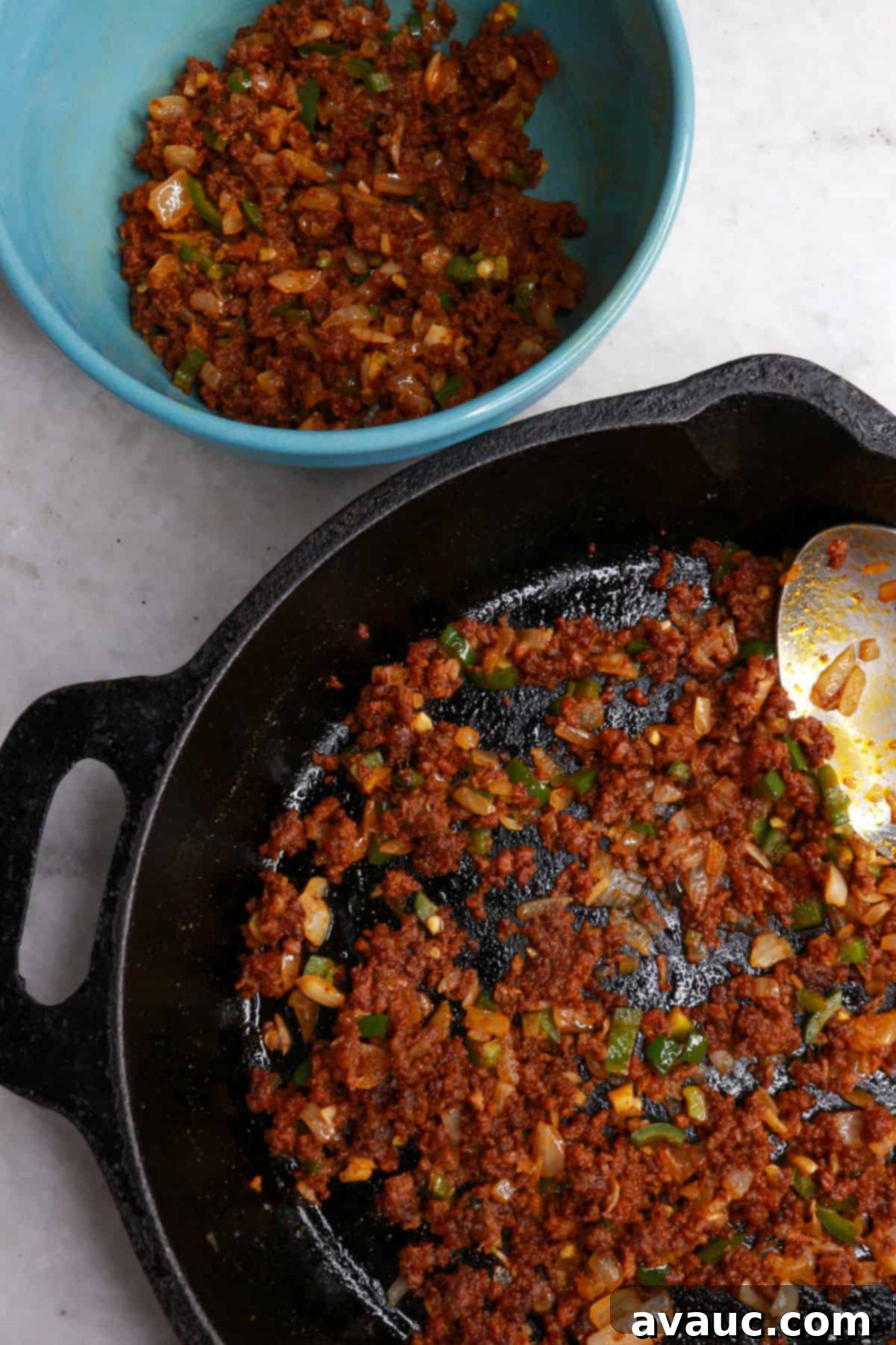 Spicy Chorizo Queso Dip 8 Half of the chorizo and veggie mixture removed from the skillet and placed in a bowl, while the other half remains in the pan, ready for layering with cheese.