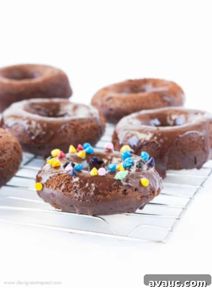 Cosmic Triple Chocolate Cake Donuts on wire rack with rainbow sprinkles