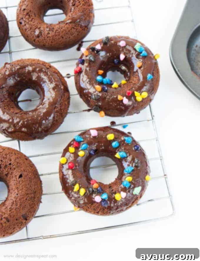 Cosmic Triple Chocolate Cake Donuts on wire rack with rainbow sprinkles