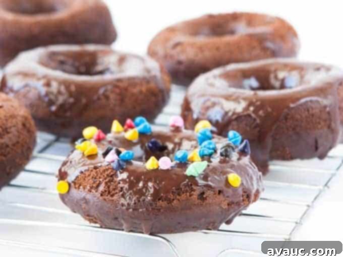 Cosmic Triple Chocolate Cake Donuts on wire rack with rainbow sprinkles