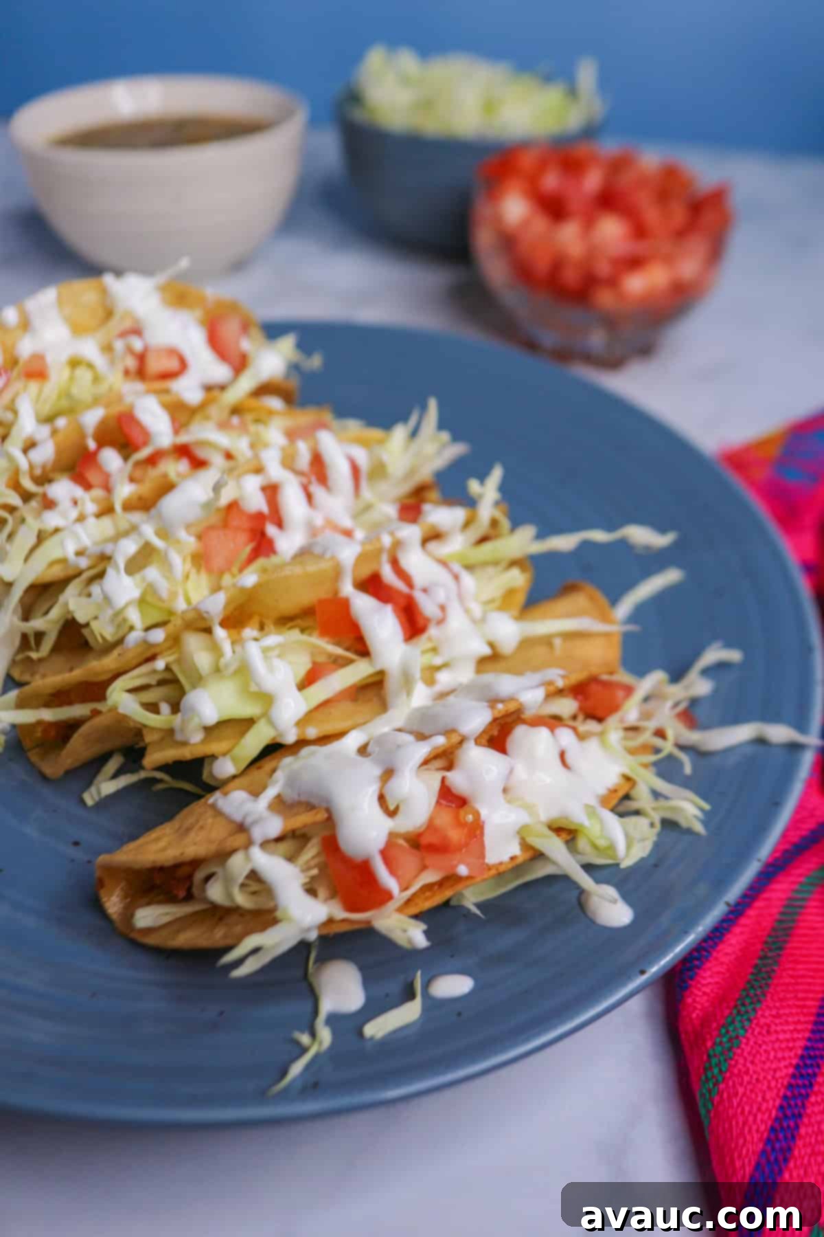 Golden Crispy Potato Tacos 2 Plate of crispy tacos de papa topped with cabbage, tomatoes and sour cream