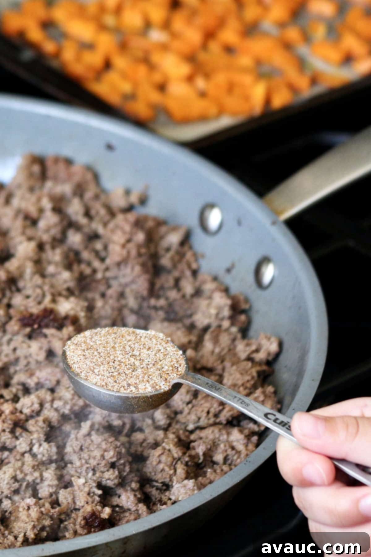 Vibrant Sweet Potato Taco Bowl 7 Adding homemade taco seasoning to cooked ground beef in a skillet.