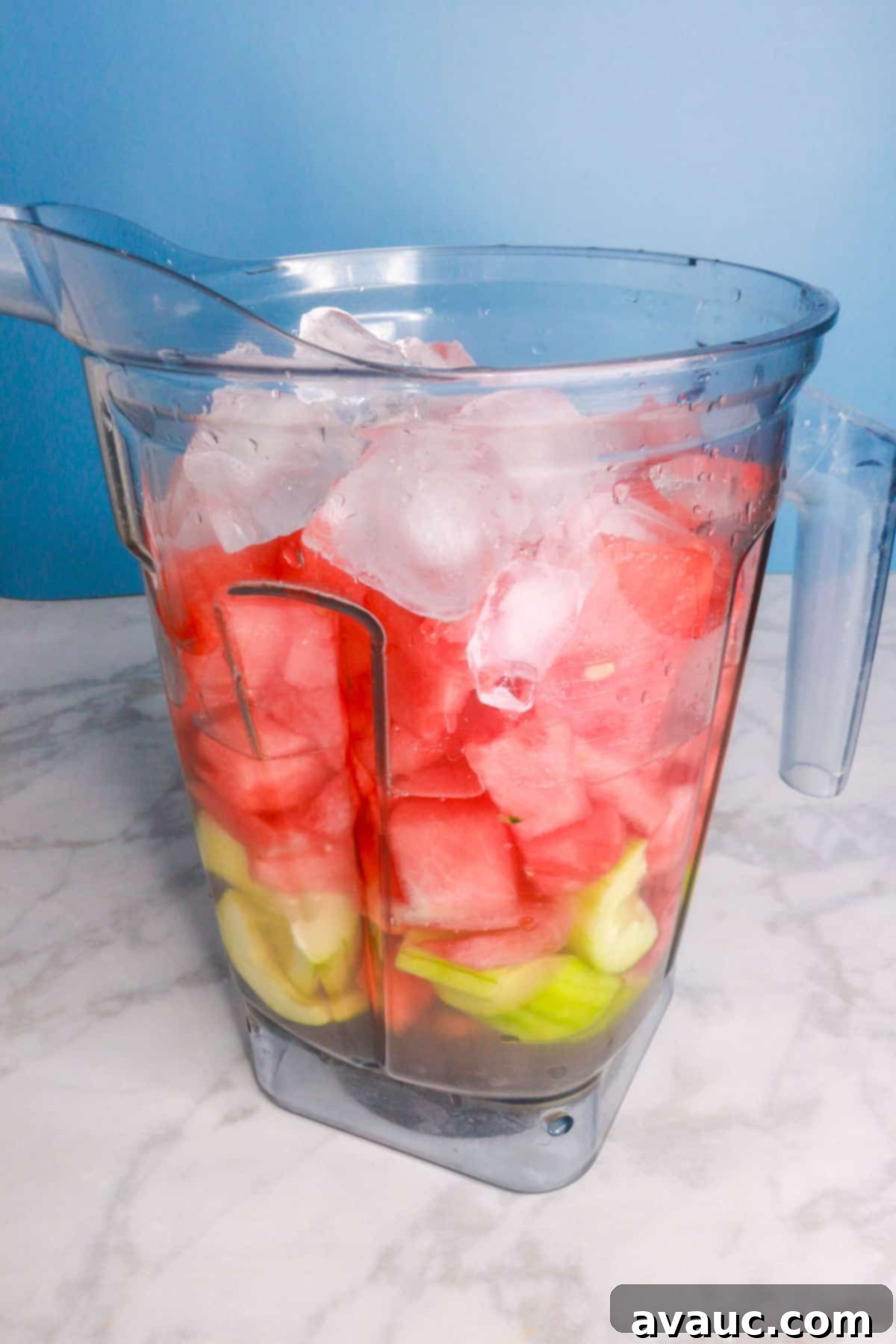Vibrant Cucumber Watermelon Cooler 7 Sliced cucumbers, diced watermelon, and ice cubes gathered in a blender pitcher, poised for blending into a refreshing agua fresca.