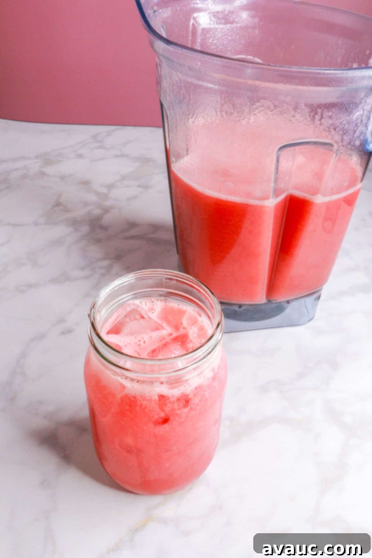 Watermelon Strawberry Agua Fresca 8 A freshly prepared glass of Watermelon Strawberry Agua Fresca, with a blender containing more in the background, showcasing the vibrant colors.