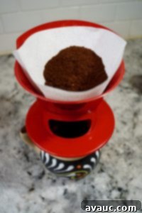 Adding coffee grounds to a pour-over filter.